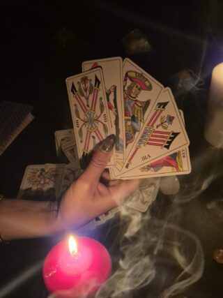 Cartomanzia rituale con tarocchi, candela rossa e atmosfera mistica